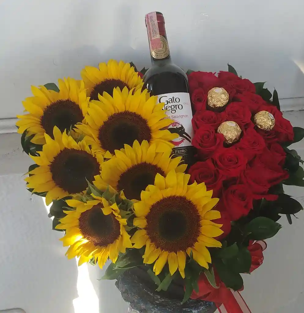 Arreglo Caja Corazón, 7girasoles,12 Rosas Rojas, Una Botella De Gato Negro Pequeña Y Tres Chocolates Ferrero, moño